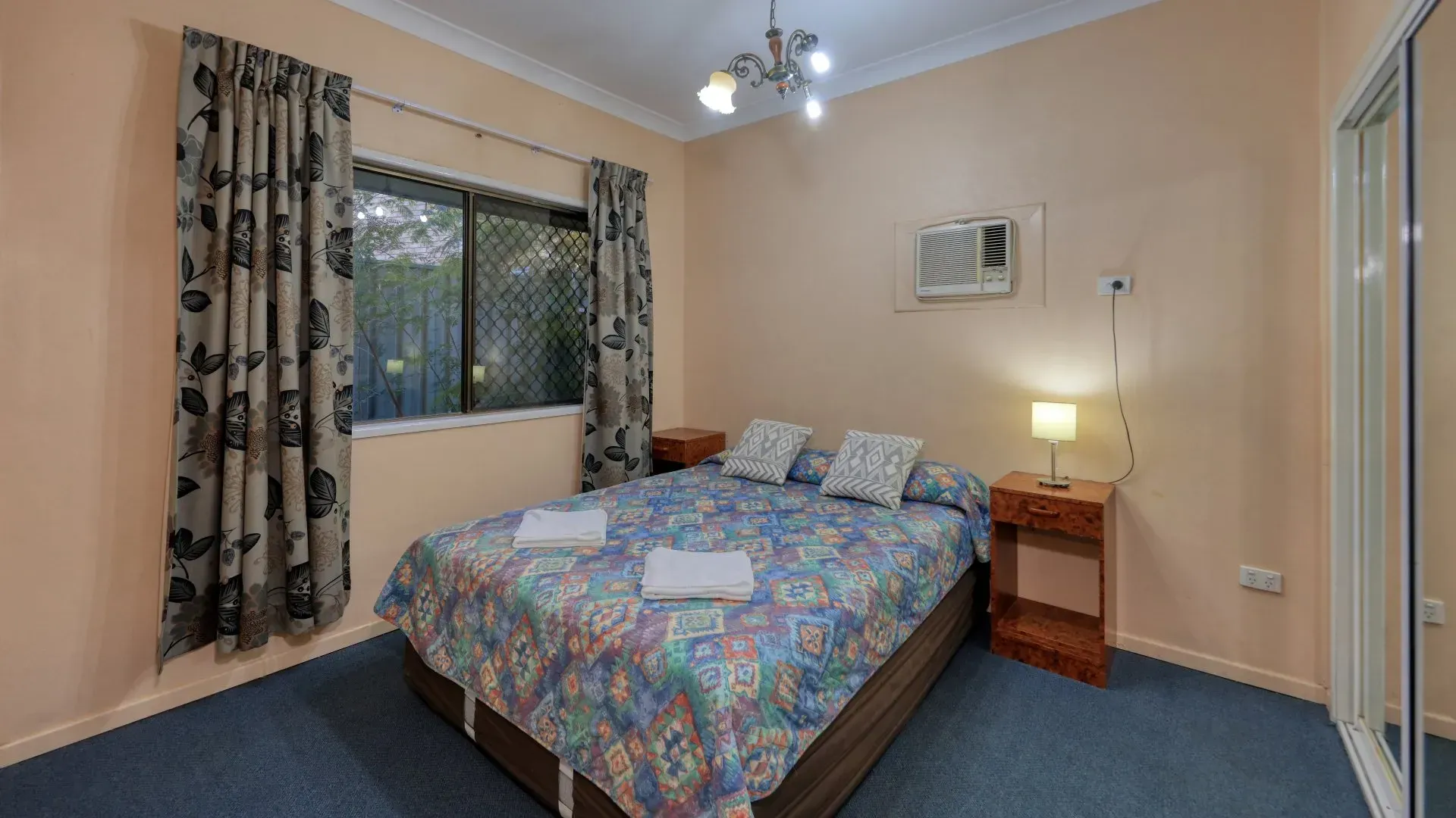 Bedroom with A Bed, Two Nightstands, a Window, Patterned Curtains, and A Mirror — Townview Motel In Mount Isa, QLD
