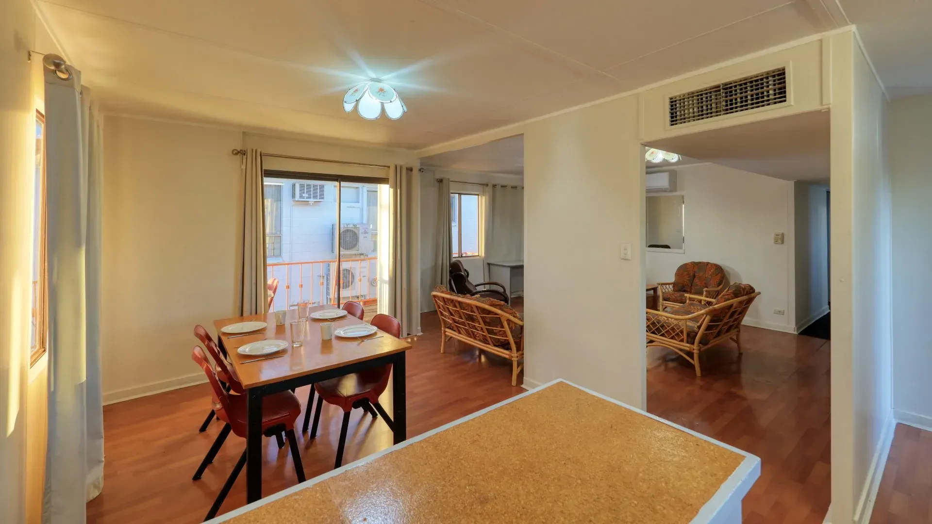 Dining Area with Table Set for Six, Leading Into a Living Room with Wicker Furniture — Townview Motel In Mount Isa, QLD