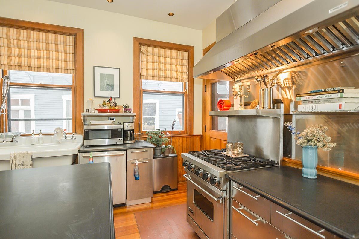 A kitchen with stainless steel appliances and a black counter top.