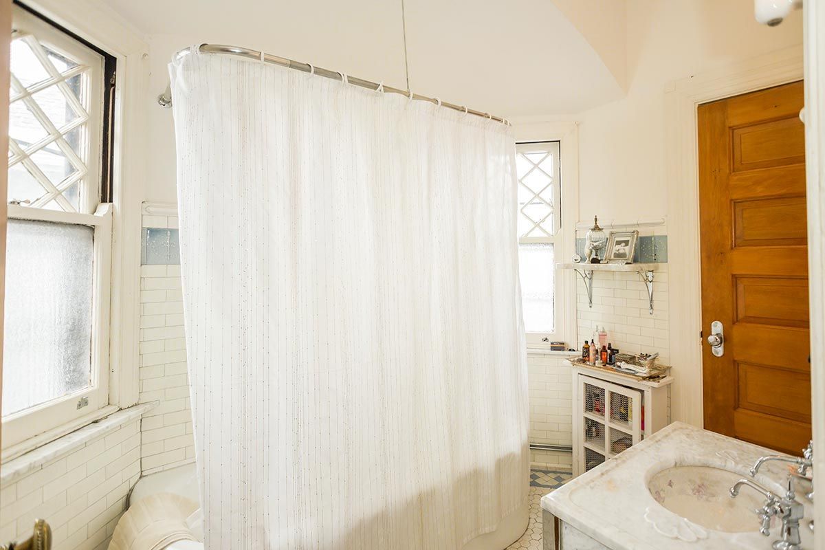 A bathroom with a white shower curtain and a sink.