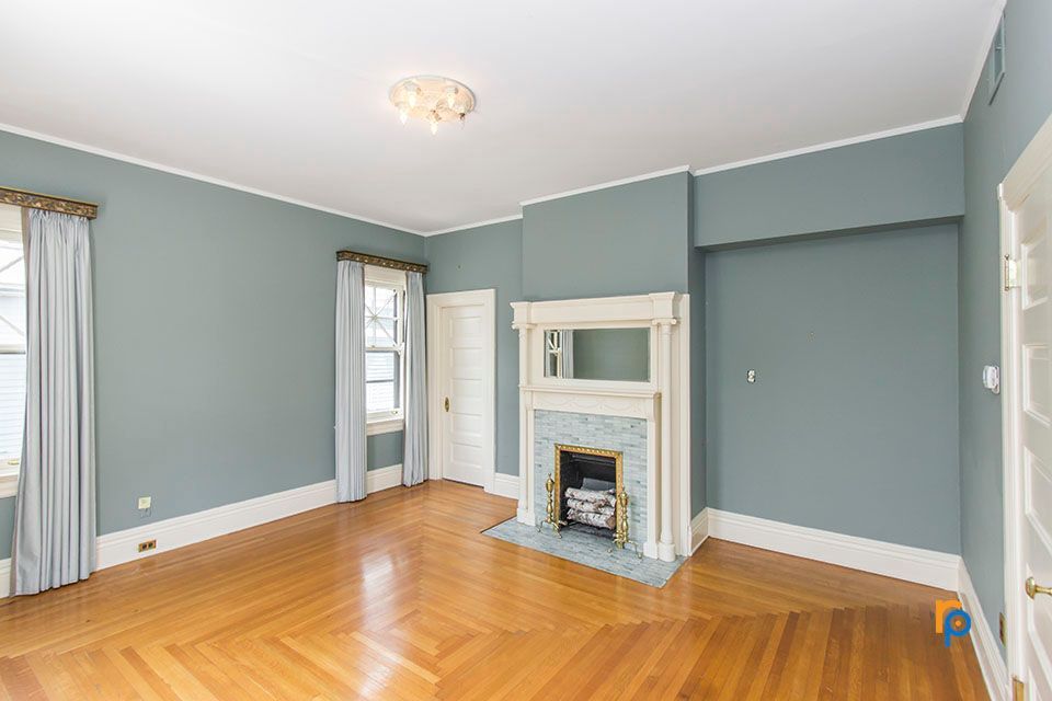 An empty living room with blue walls and a fireplace.