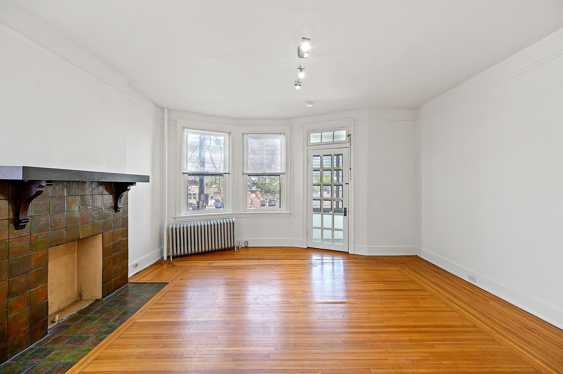 An empty living room with hardwood floors and a fireplace.
