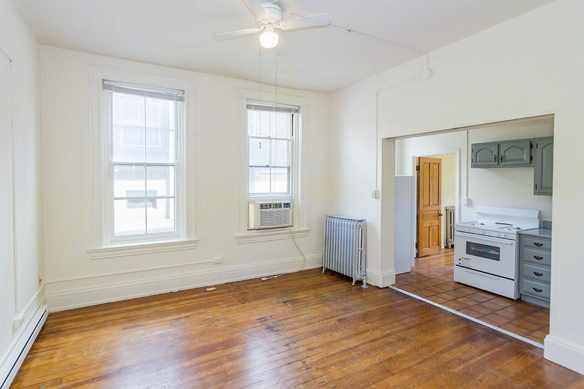 An empty living room with hardwood floors and a ceiling fan.