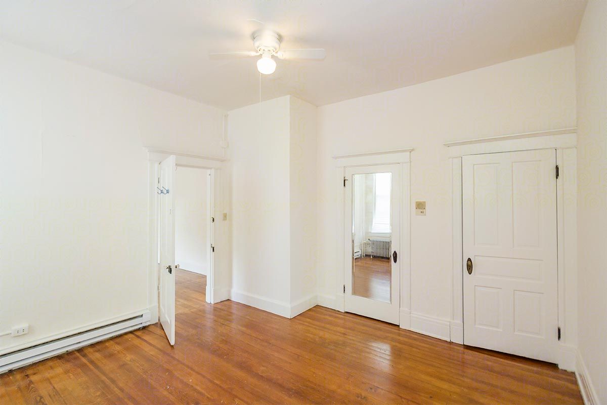 An empty room with hardwood floors and white walls.