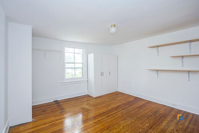 An empty room with hardwood floors , white walls and shelves.