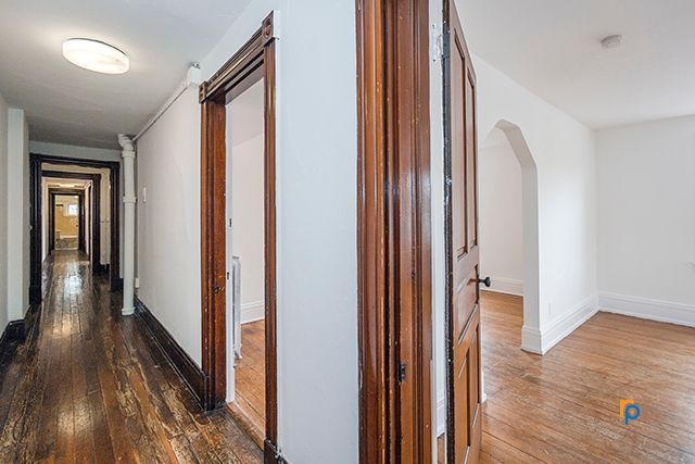 An empty hallway with wooden floors and white walls in a house.