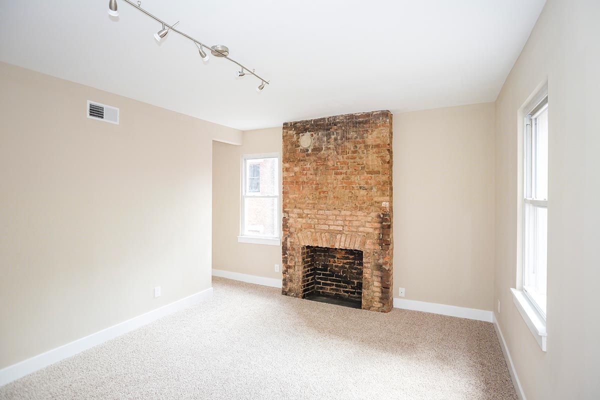 An empty living room with a fireplace and a window.