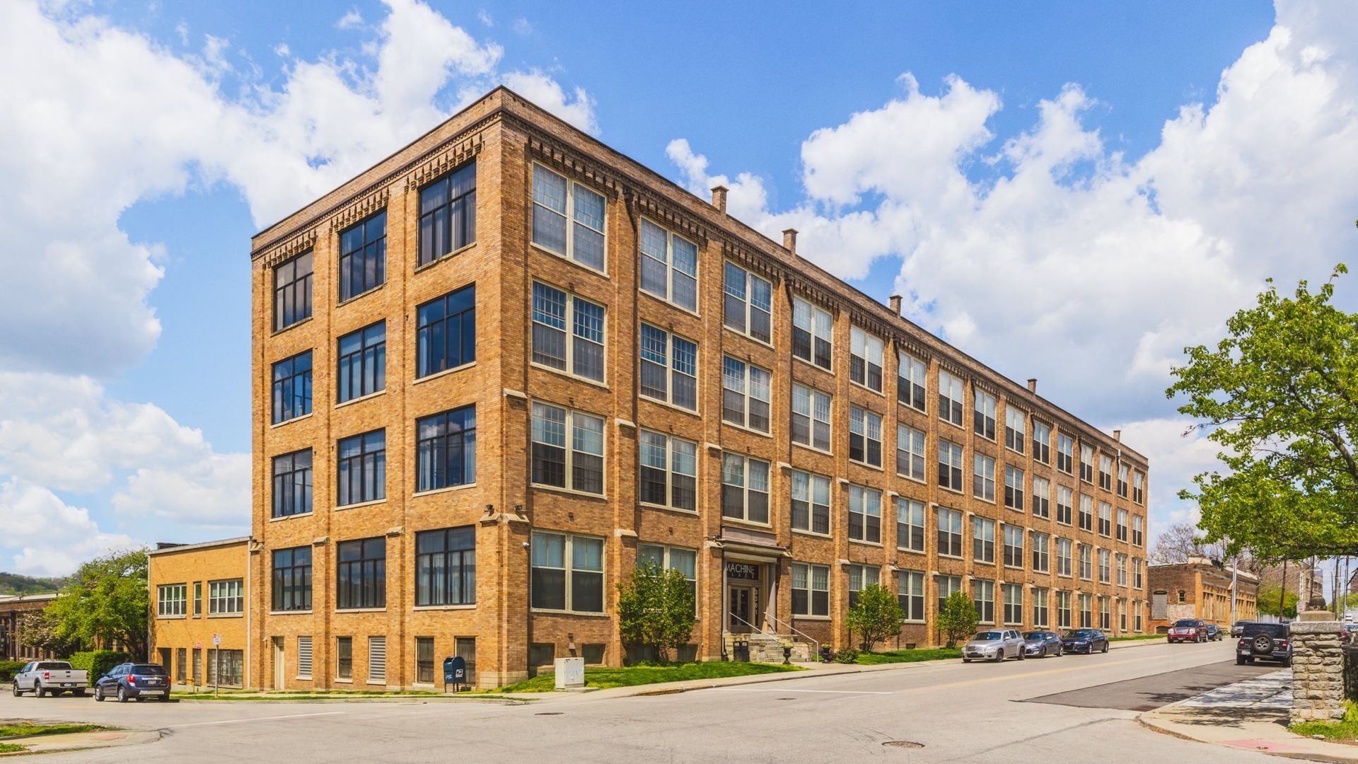 A large brick building with a lot of windows and cars parked in front of it.