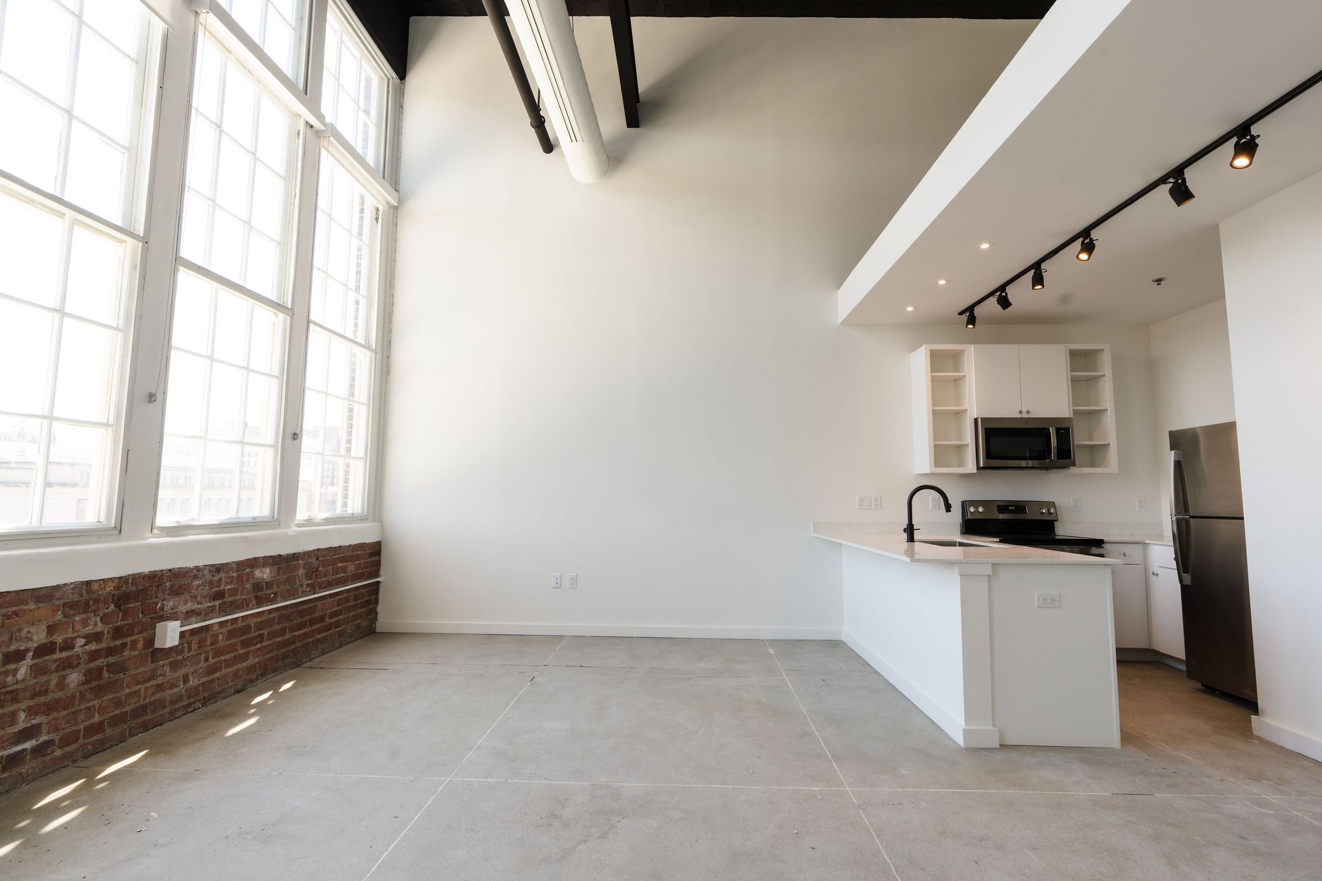 An empty apartment with a kitchen and a large window