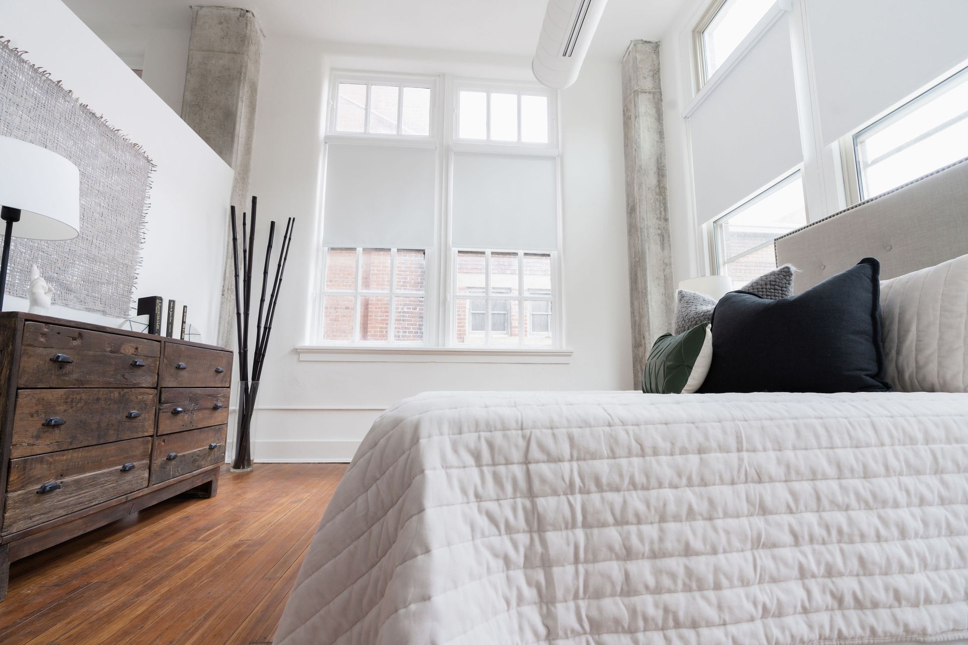 A bedroom with a bed , dresser , and window.