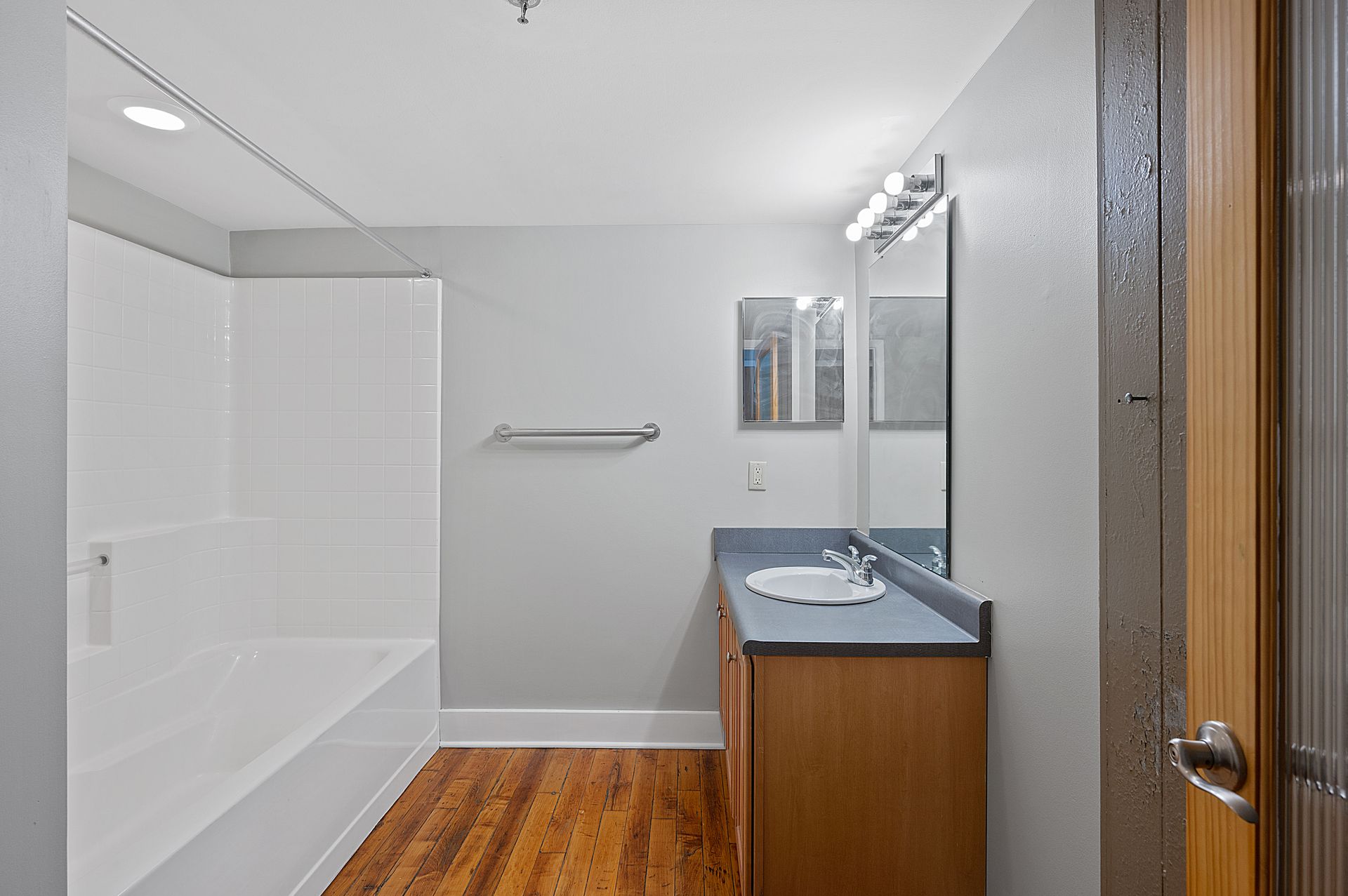 A bathroom with a sink , tub and mirror.