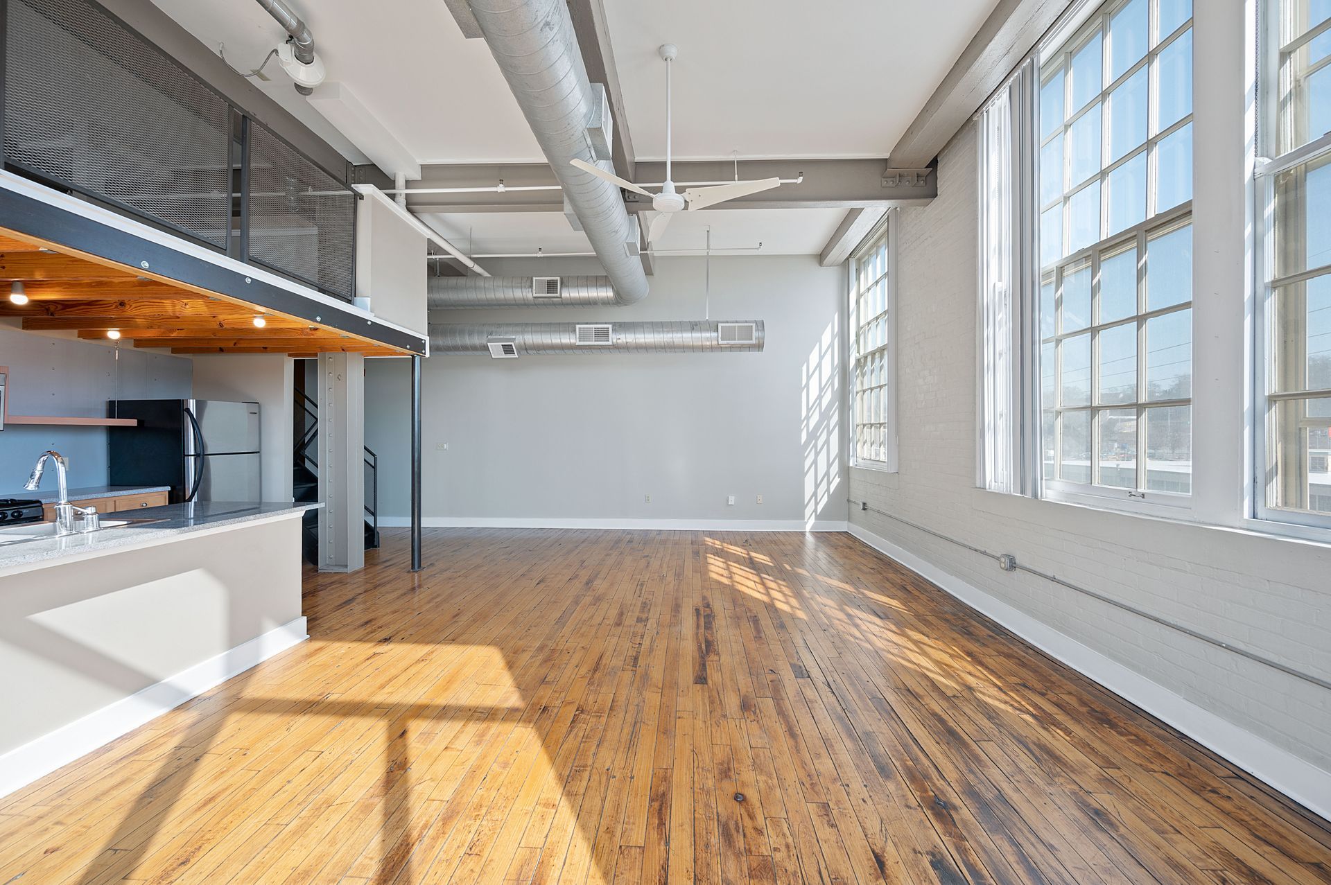 A large empty room with hardwood floors and lots of windows.