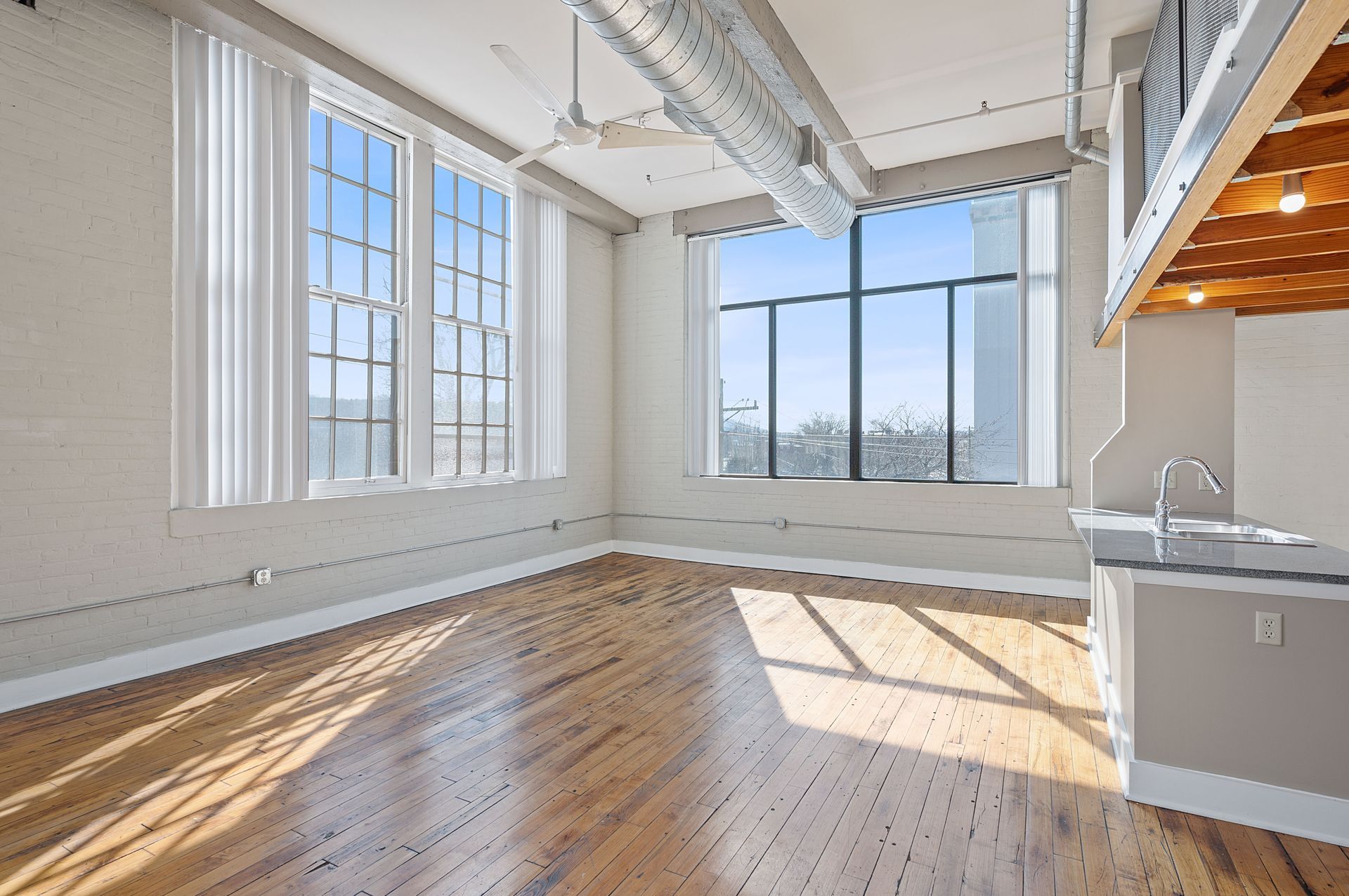 A large empty room with hardwood floors and lots of windows.