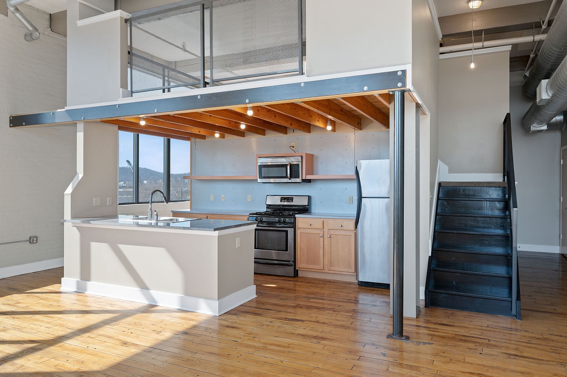 An empty kitchen with a staircase leading to the second floor