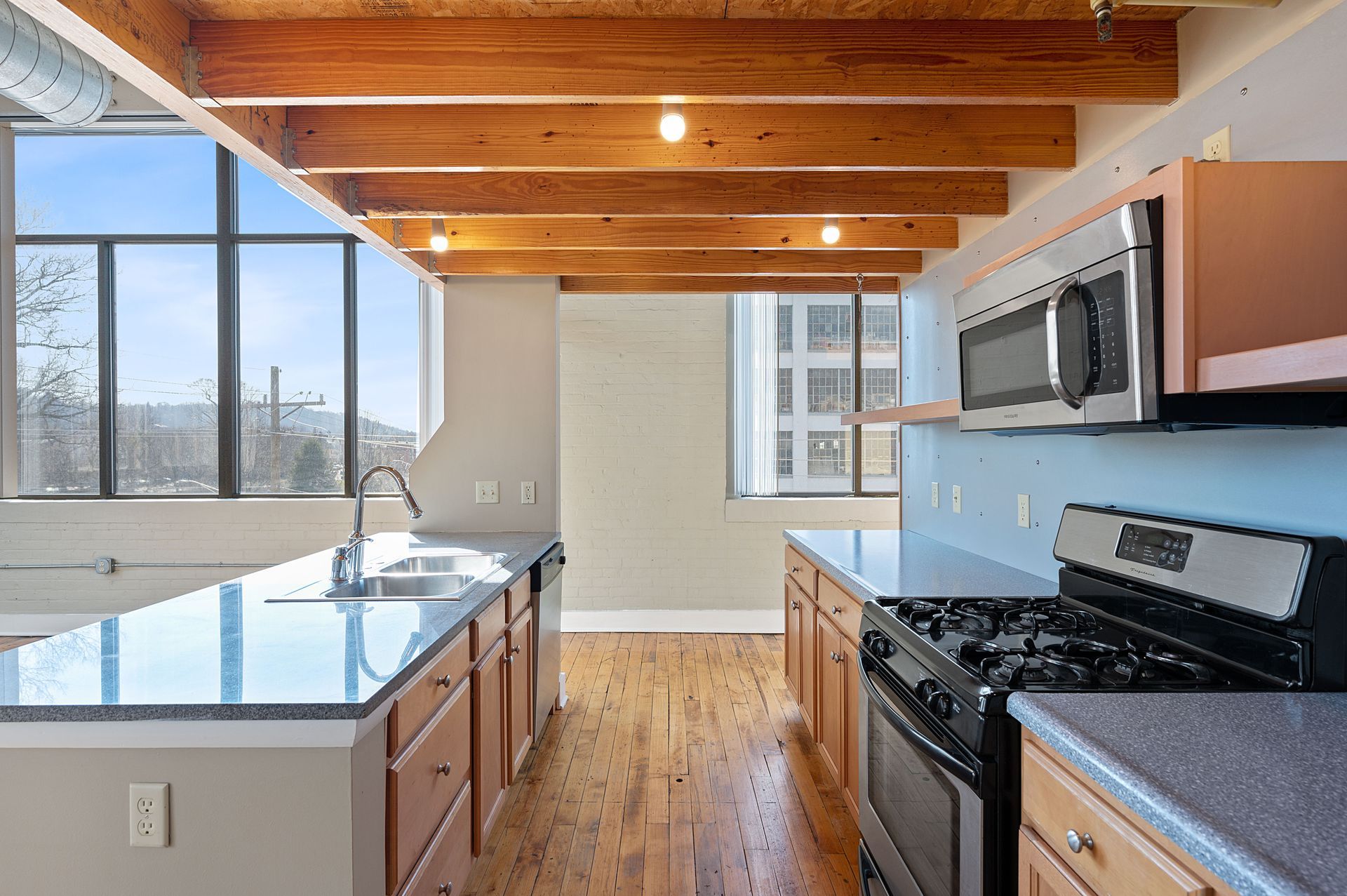 A kitchen with stainless steel appliances and wooden beams