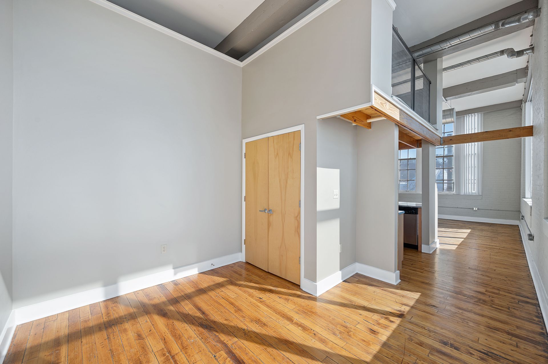 A large empty room with hardwood floors and white walls.