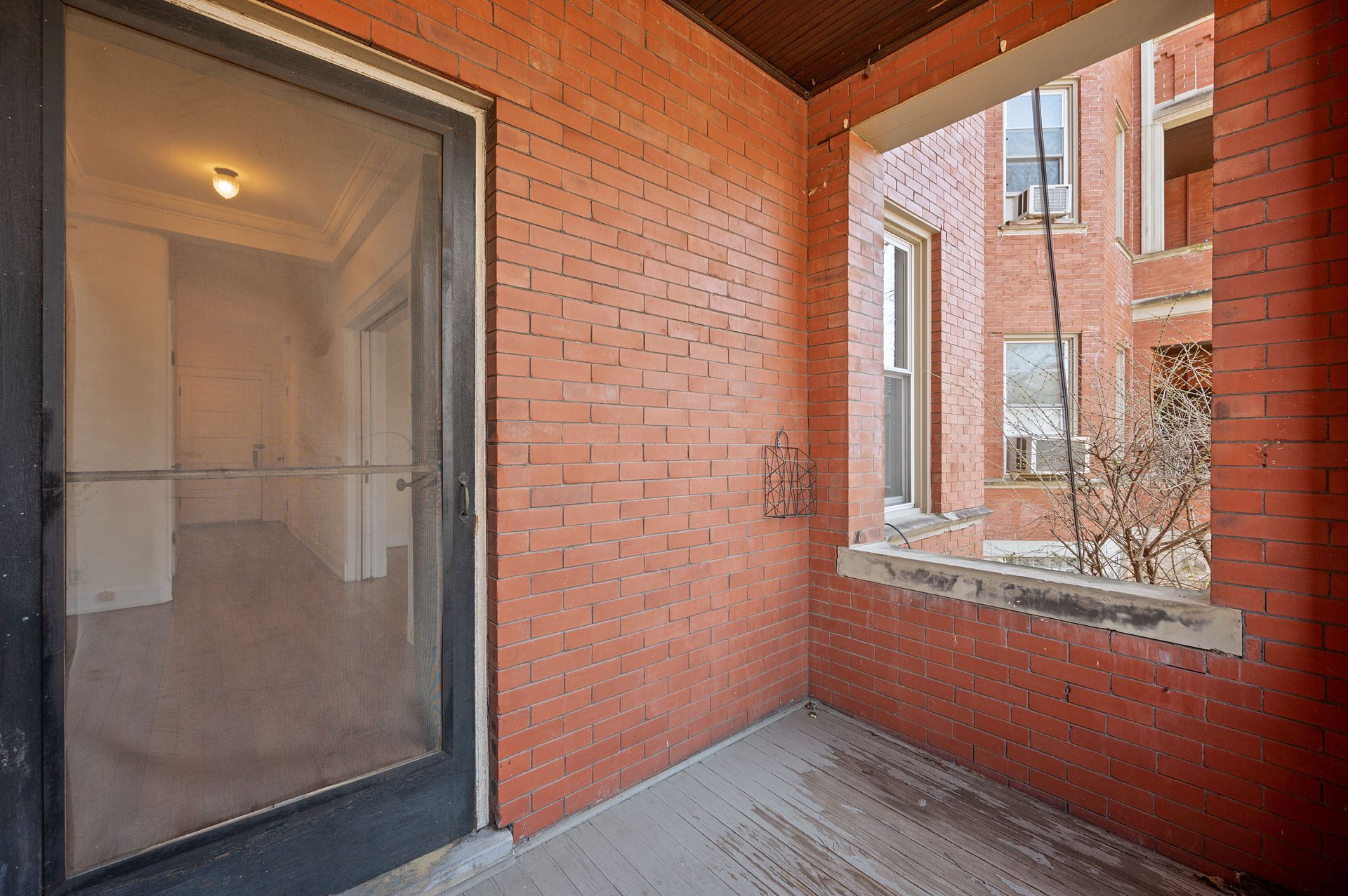 A brick porch with a sliding glass door and a window
