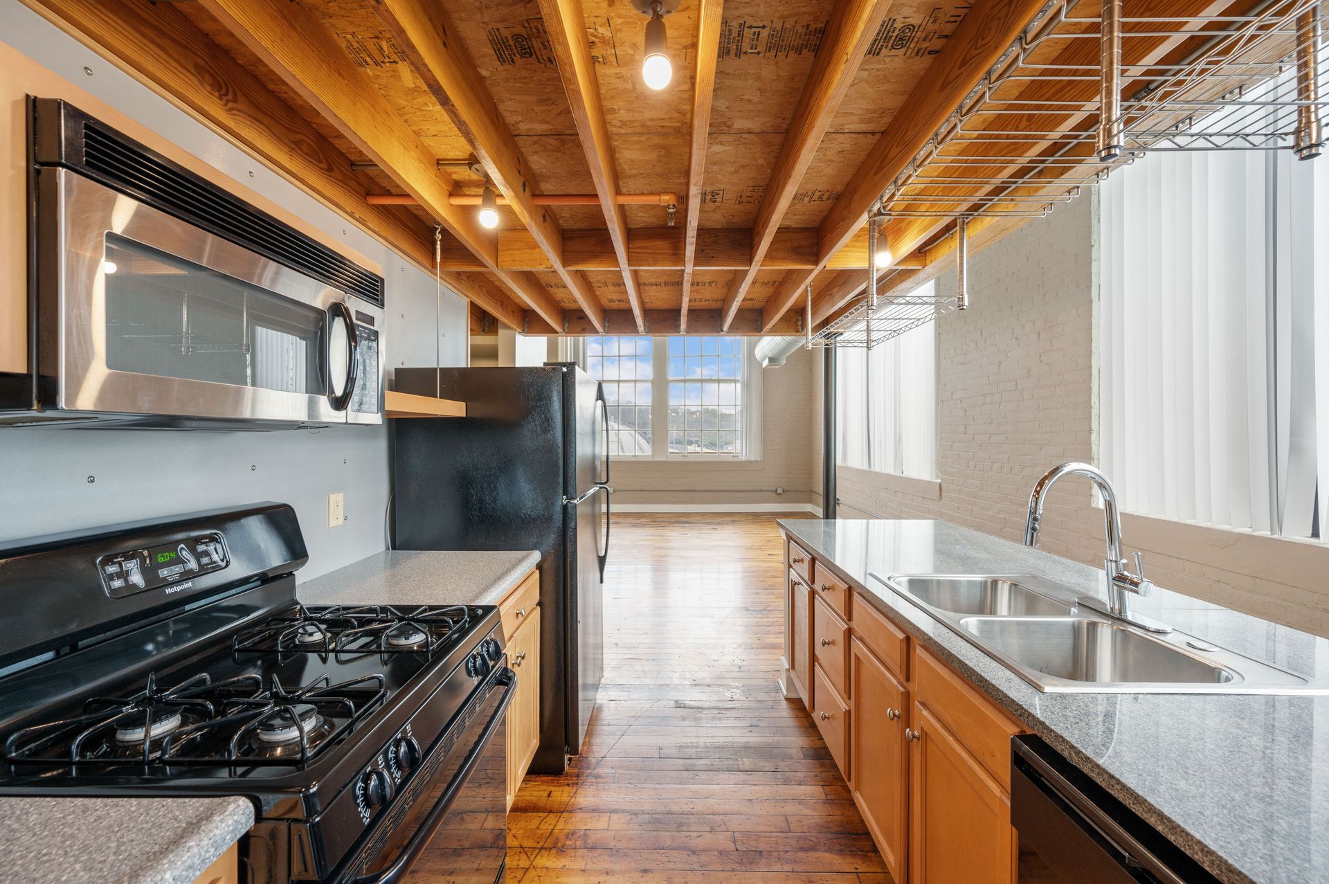 A kitchen with a stove , sink , refrigerator and microwave.