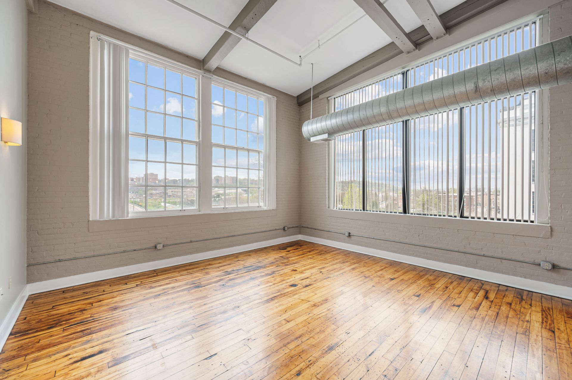 A large empty room with wooden floors and lots of windows.