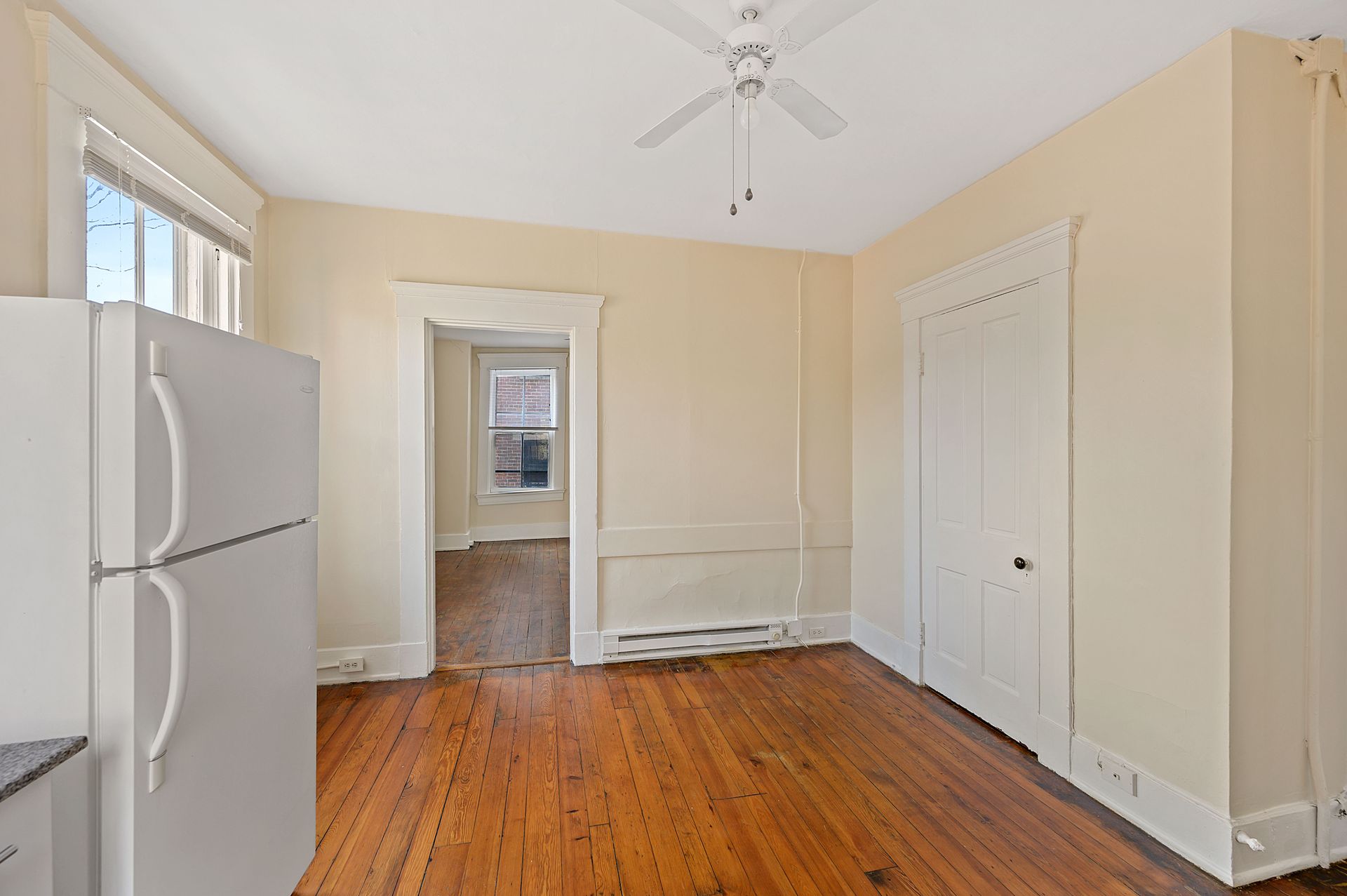 A kitchen with a refrigerator and a ceiling fan