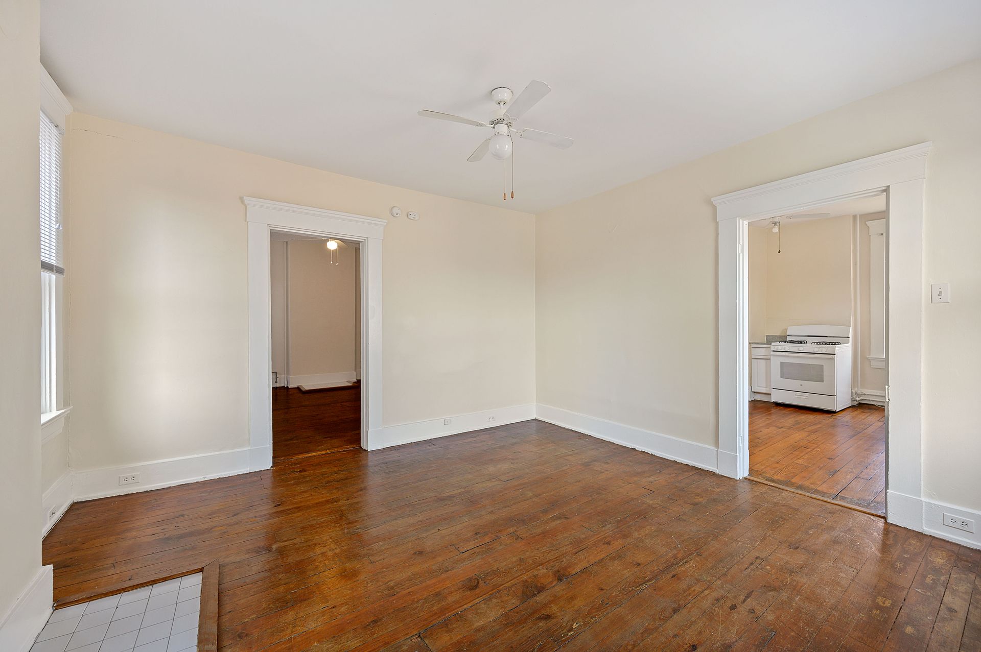 An empty living room with hardwood floors and a ceiling fan.