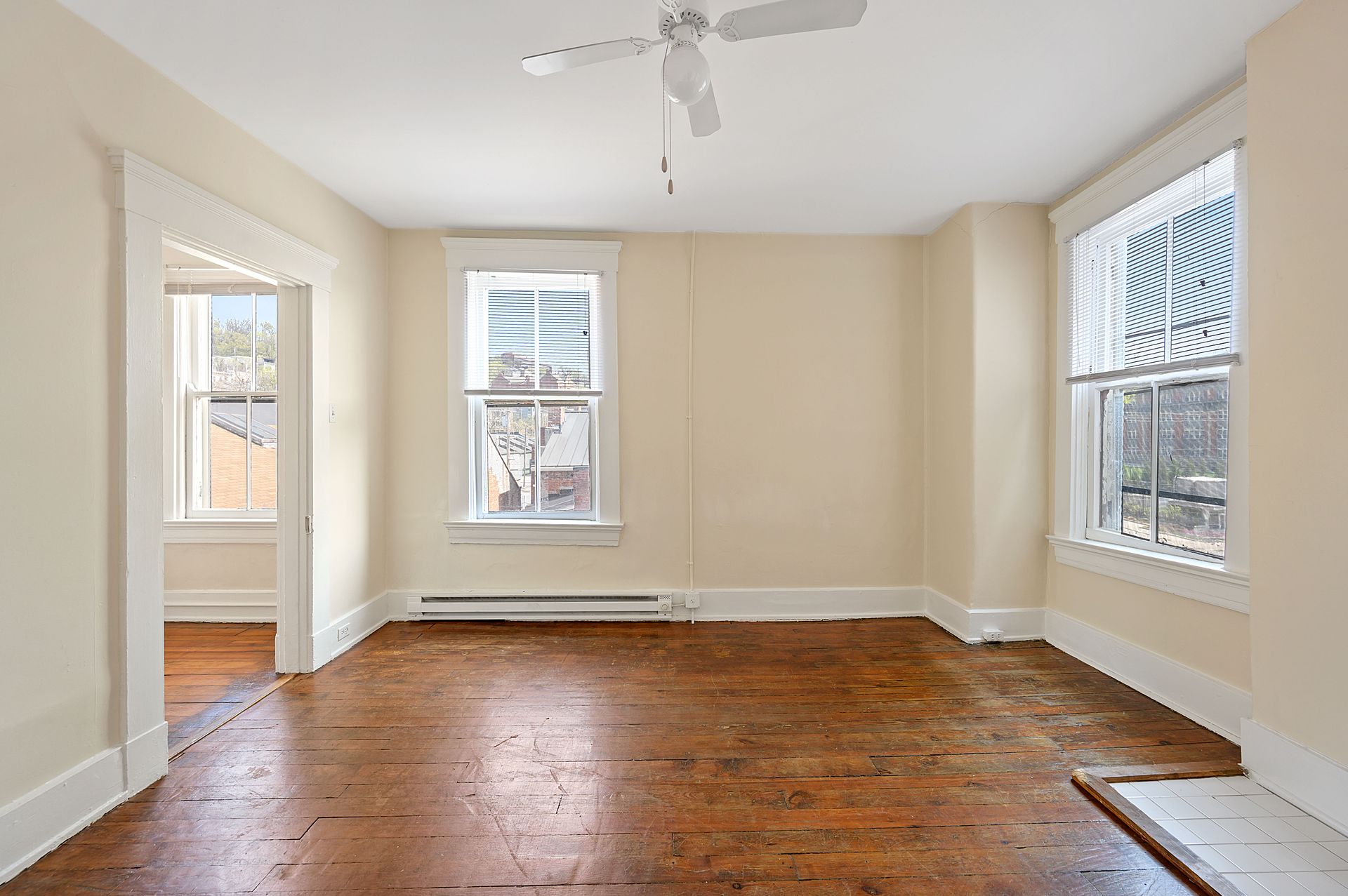An empty living room with hardwood floors and a ceiling fan