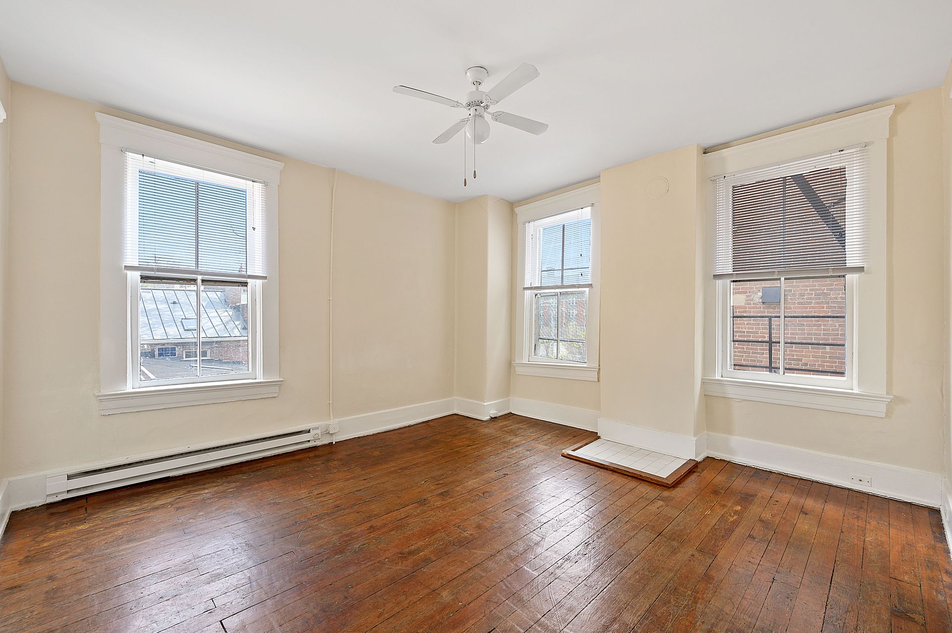 An empty room with hardwood floors and a ceiling fan