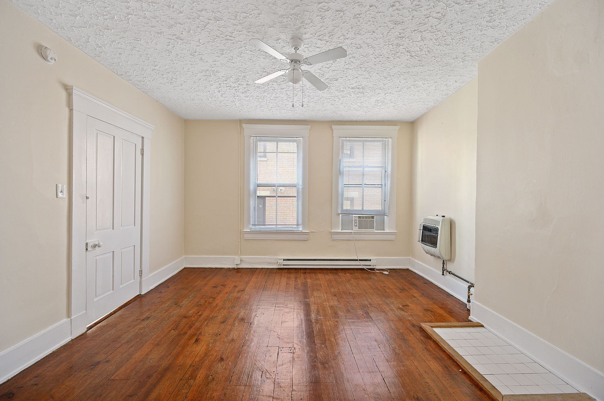 An empty room with hardwood floors and a ceiling fan