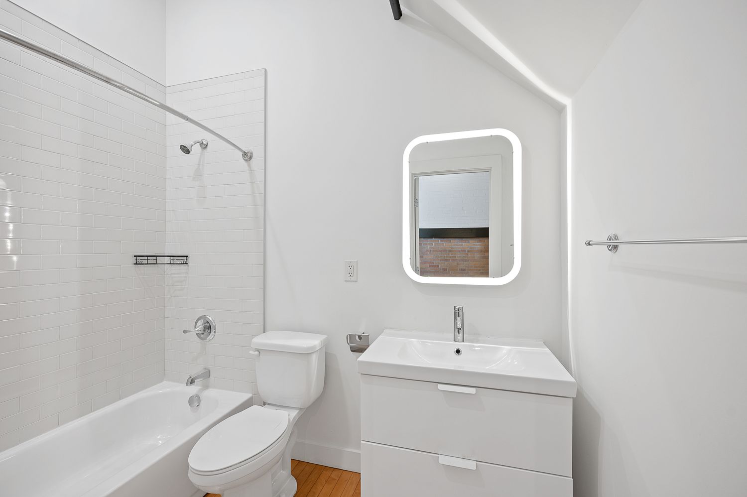 A bathroom with a toilet , sink , bathtub and mirror.