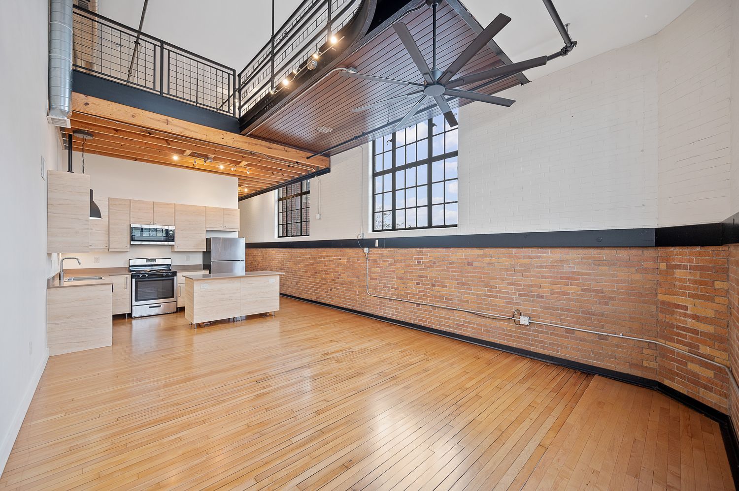 An empty room with hardwood floors and a ceiling fan