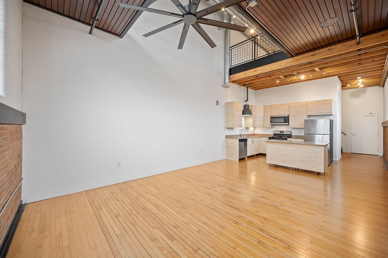 An empty room with a kitchen and a ceiling fan
