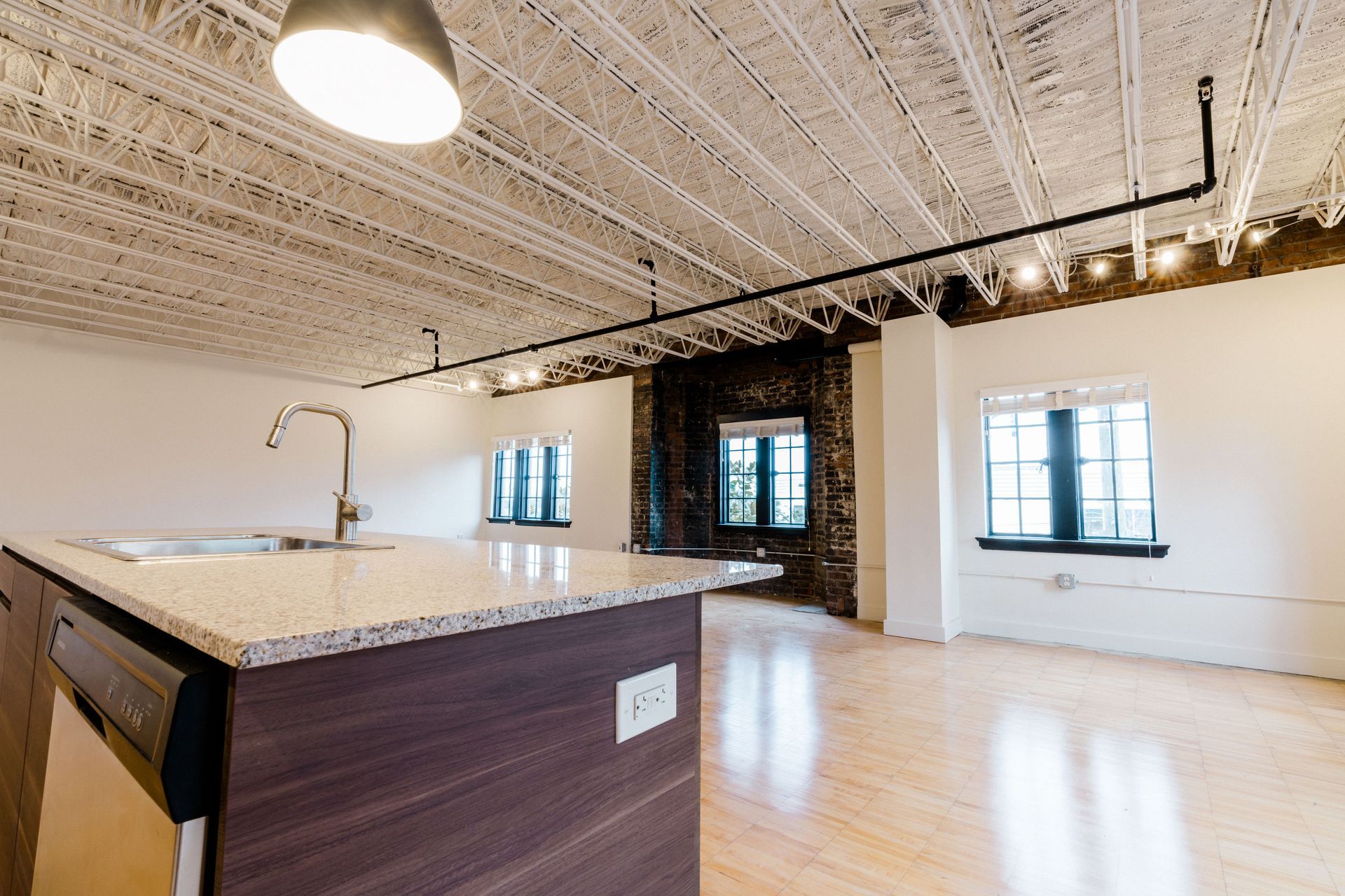 An empty kitchen with a large island and a sink.