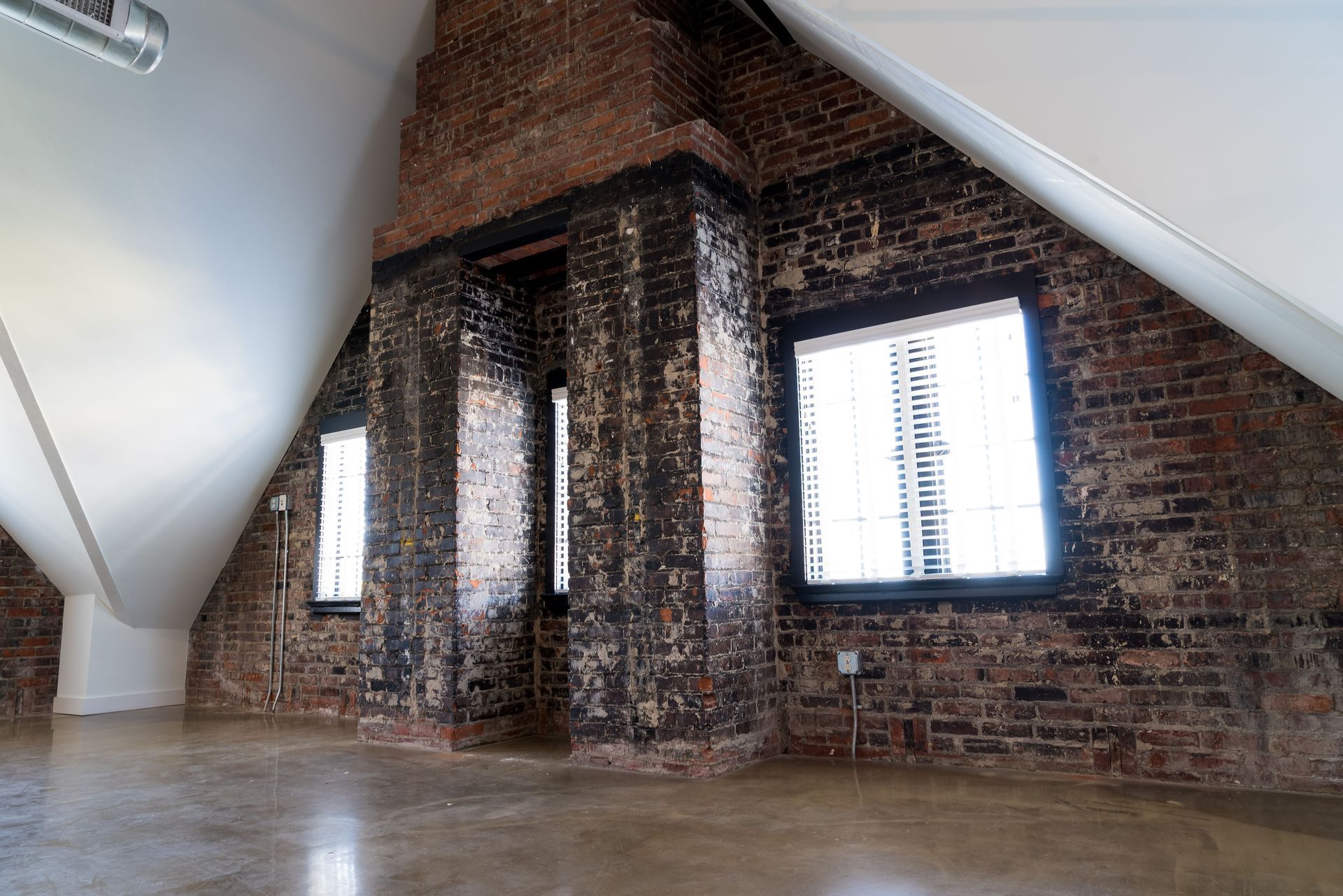 An empty attic with brick walls and windows