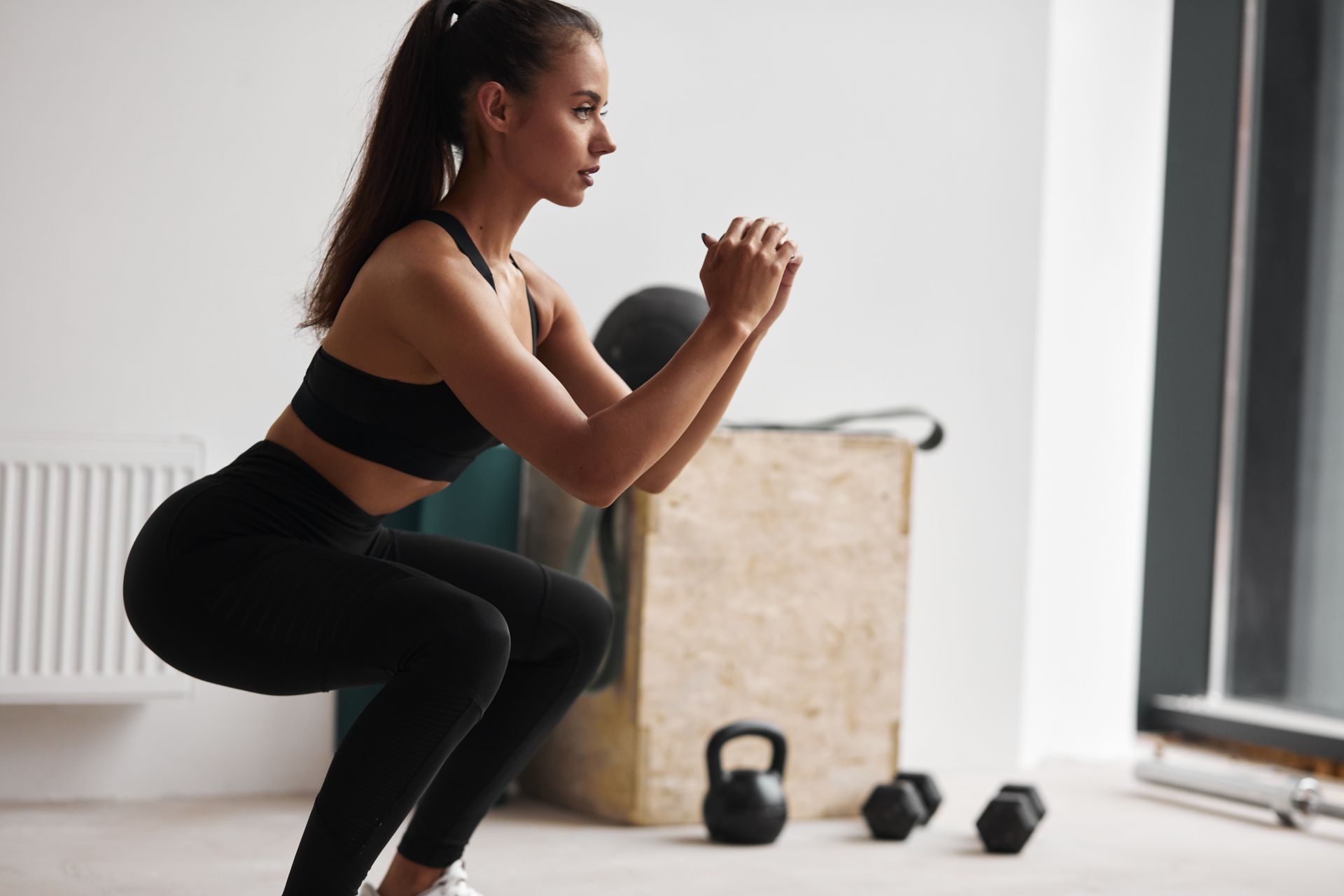 A woman is squatting on the floor in a gym.