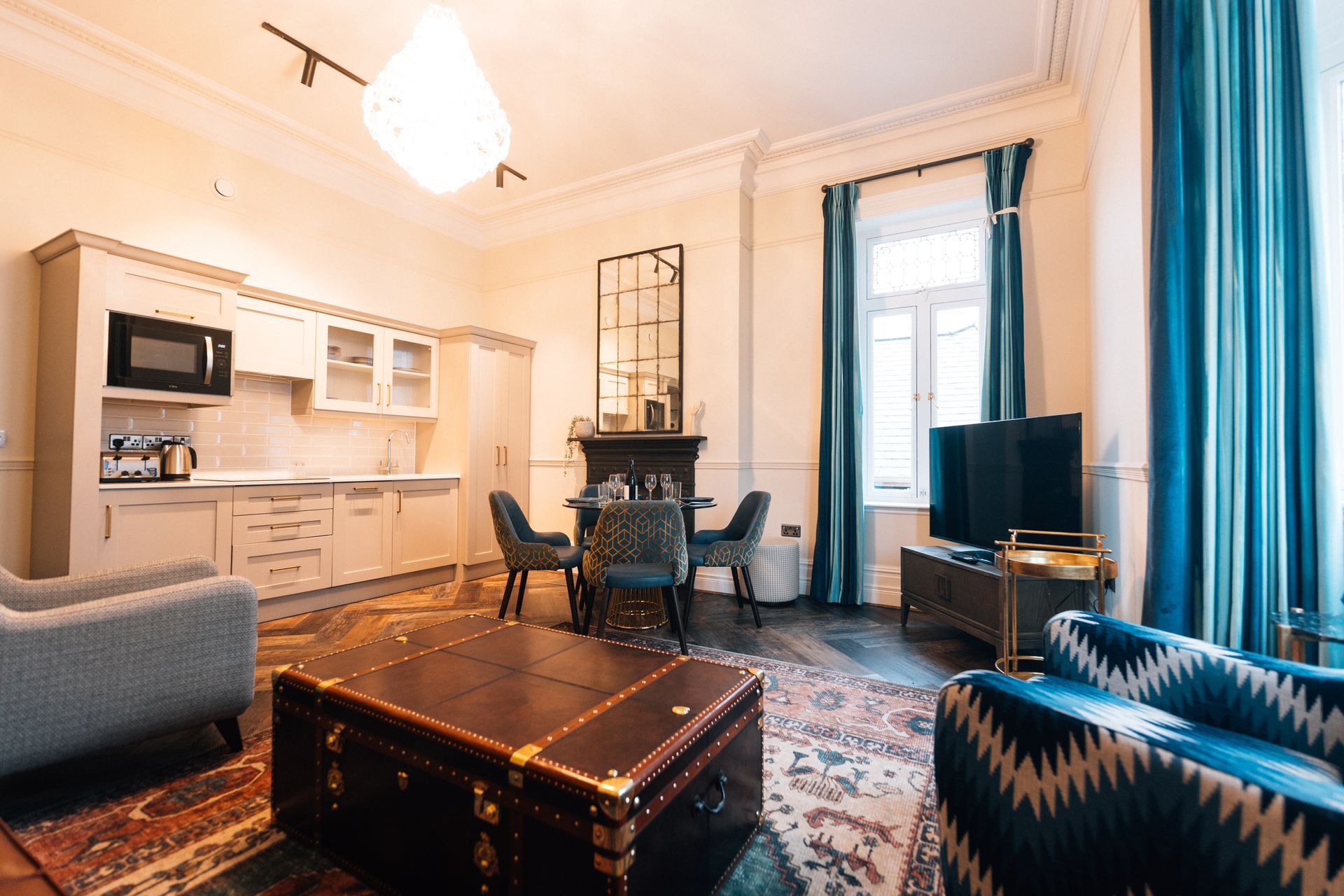An open-plan living space with a kitchenette, dining area, and seating. 