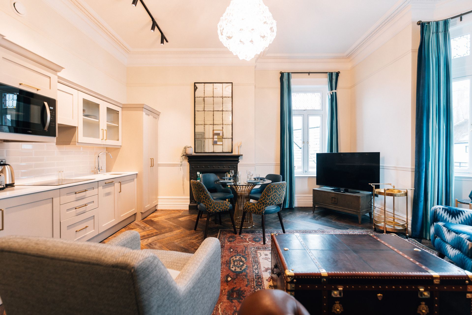 Living area with a kitchen, dining table, seating, and a TV. 