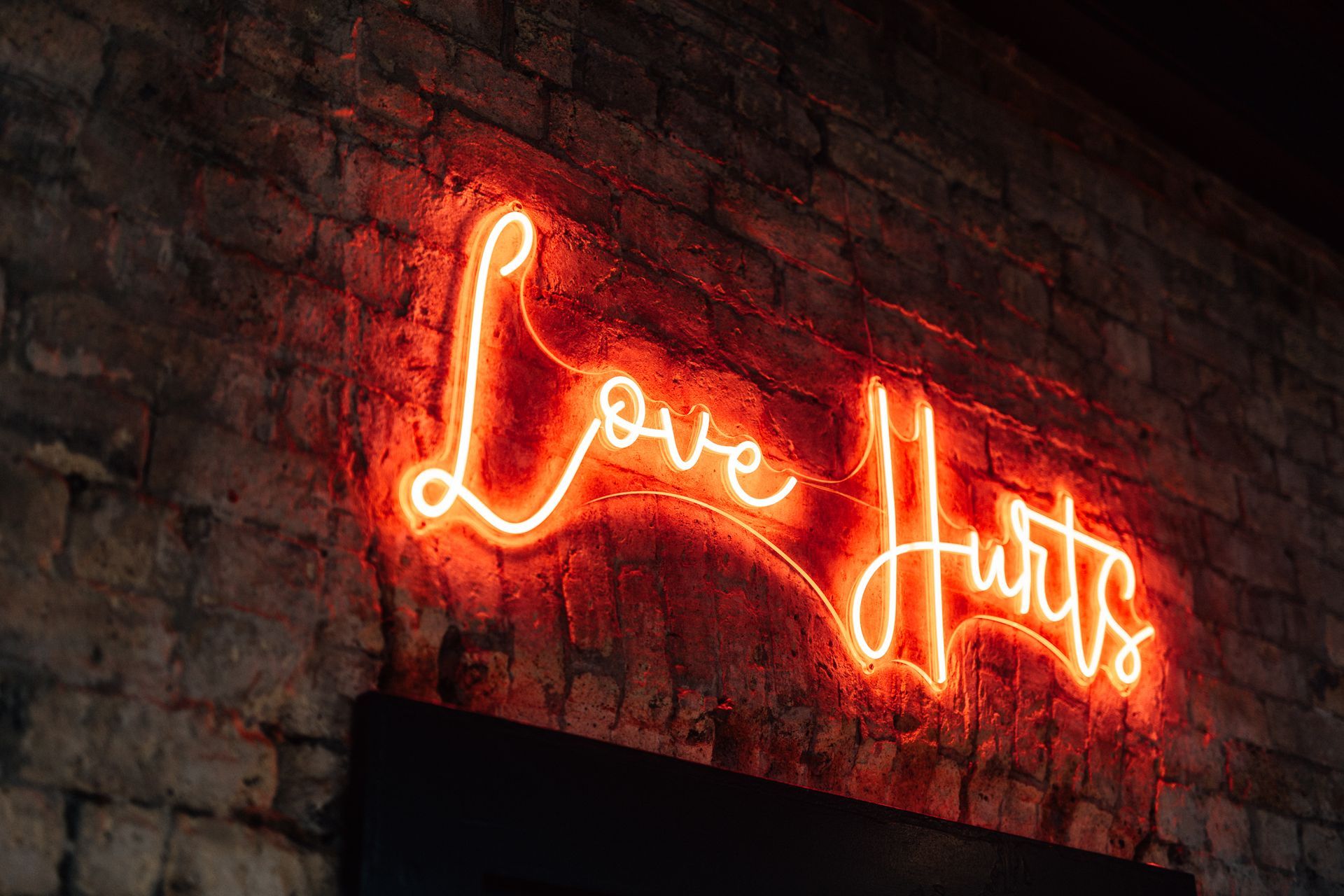 Red neon sign on a brick wall; text reads 
