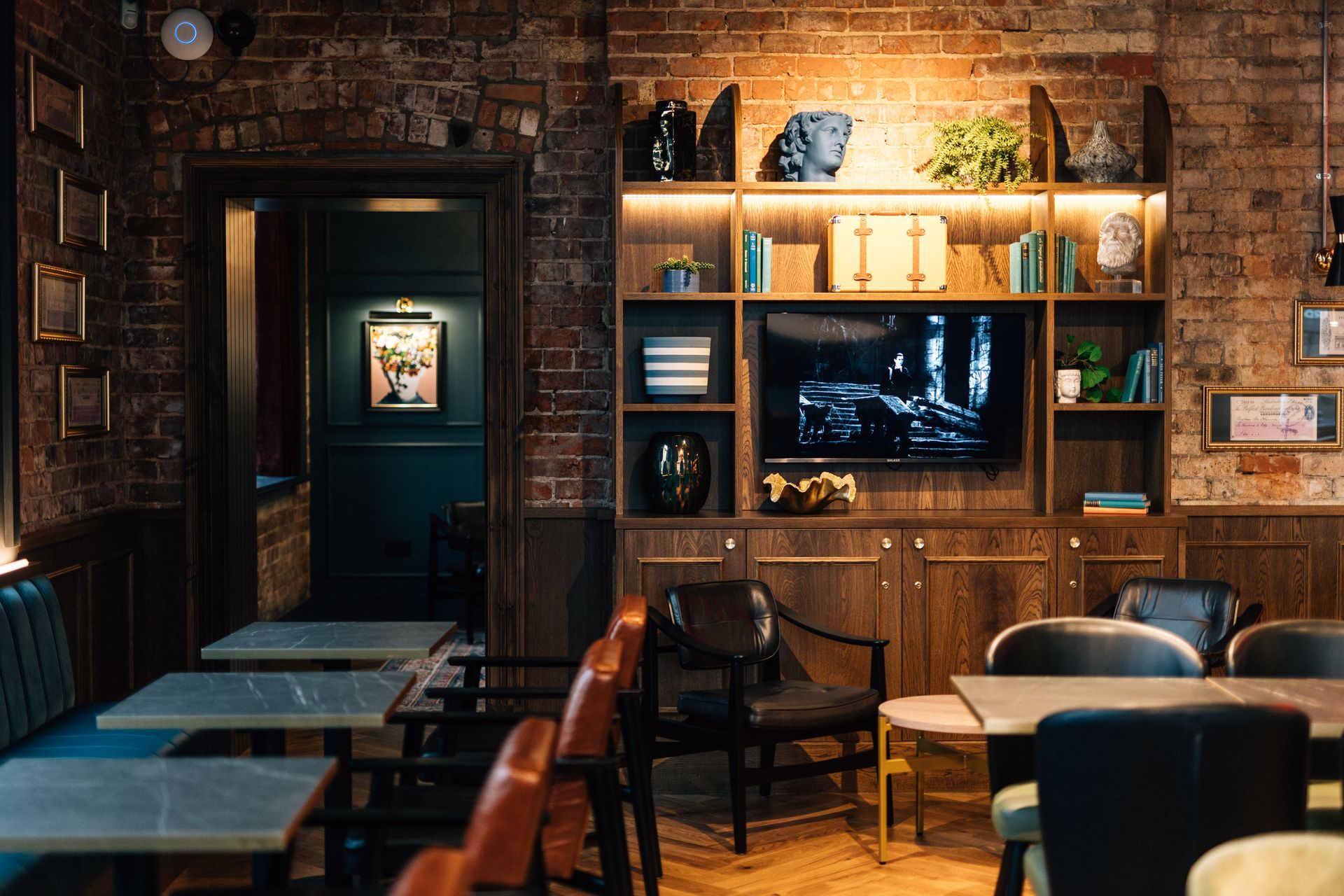 Interior of a bar with brick walls, wooden shelving, and tables.