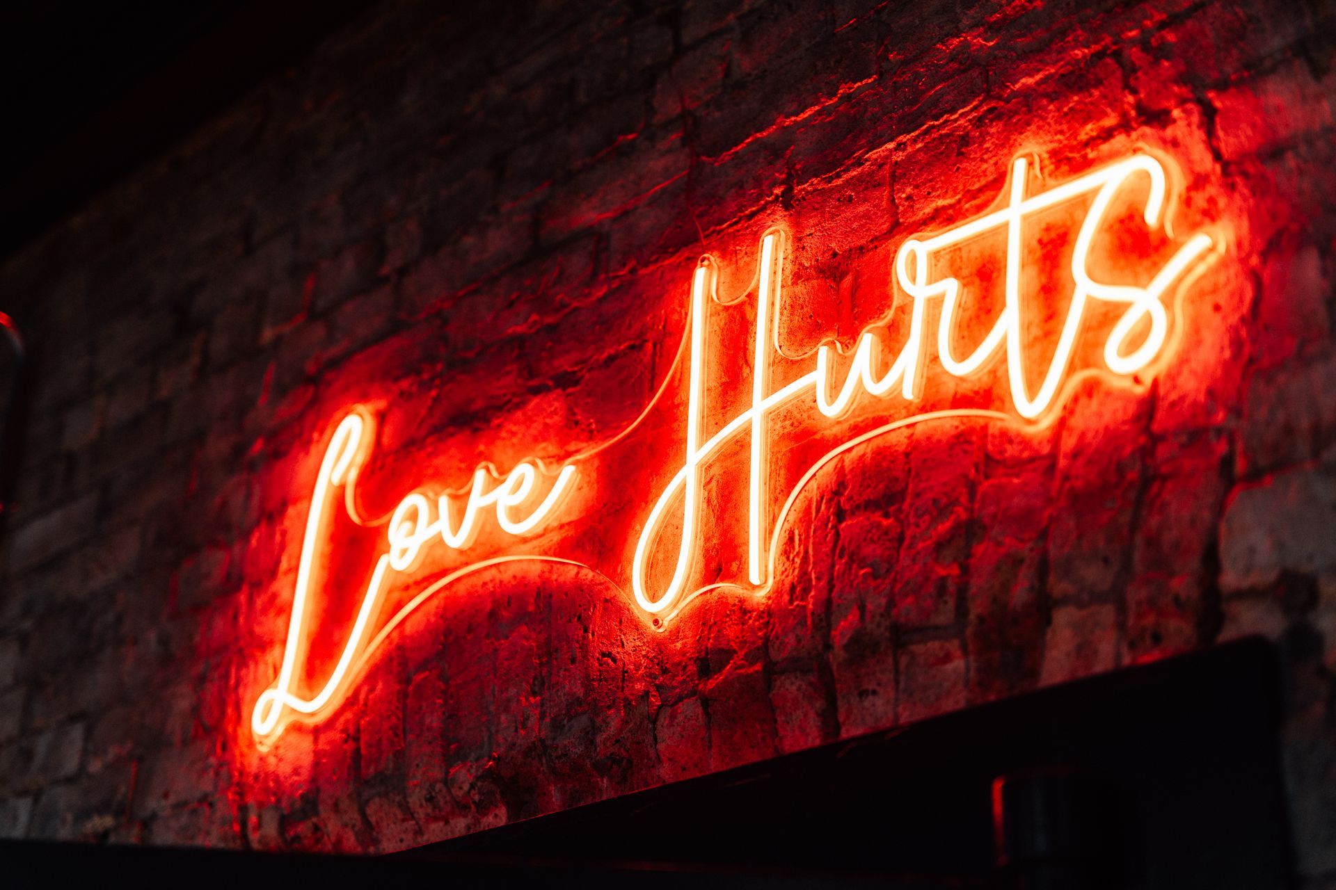 Bright red neon sign on a brick wall that reads,