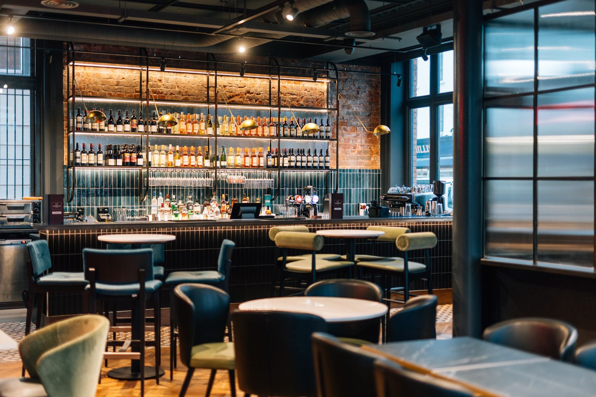 Interior of a stylish bar with well-stocked shelves, tables, and chairs in front.