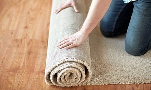 A professional unrolling a carpet for a customer