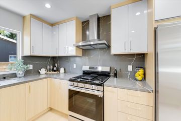 Modern kitchen with gray countertops, white and wood cabinets, and stainless steel appliances.