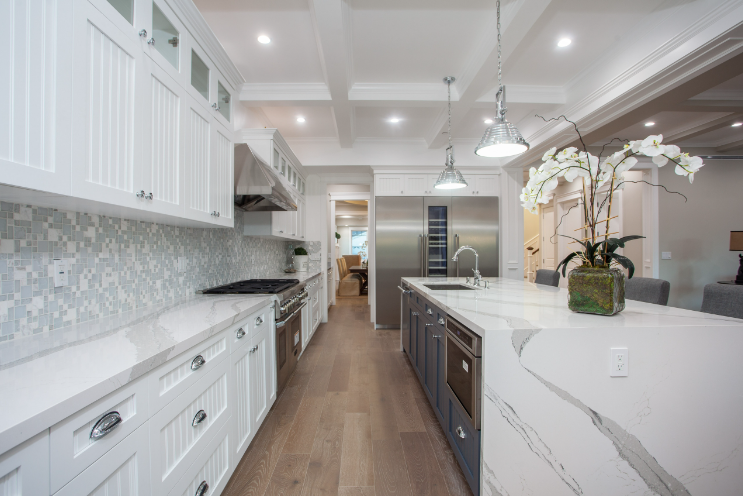 White kitchen with marble countertops, stainless steel appliances, and wood floors.