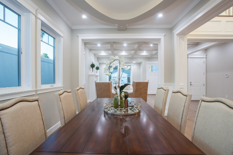 Formal dining room with long wooden table and upholstered chairs, recessed lighting, and ornate moldings.