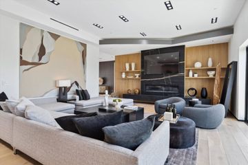 Modern living room with fireplace, artwork, and gray furniture.