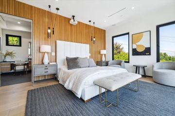 Modern bedroom with wood accent wall, large bed, and seating area.