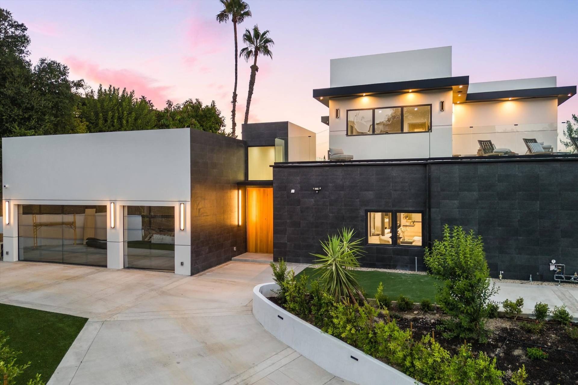 A modern house with a garage and palm trees in the background