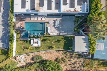 An aerial view of a large house with a swimming pool and tennis court.