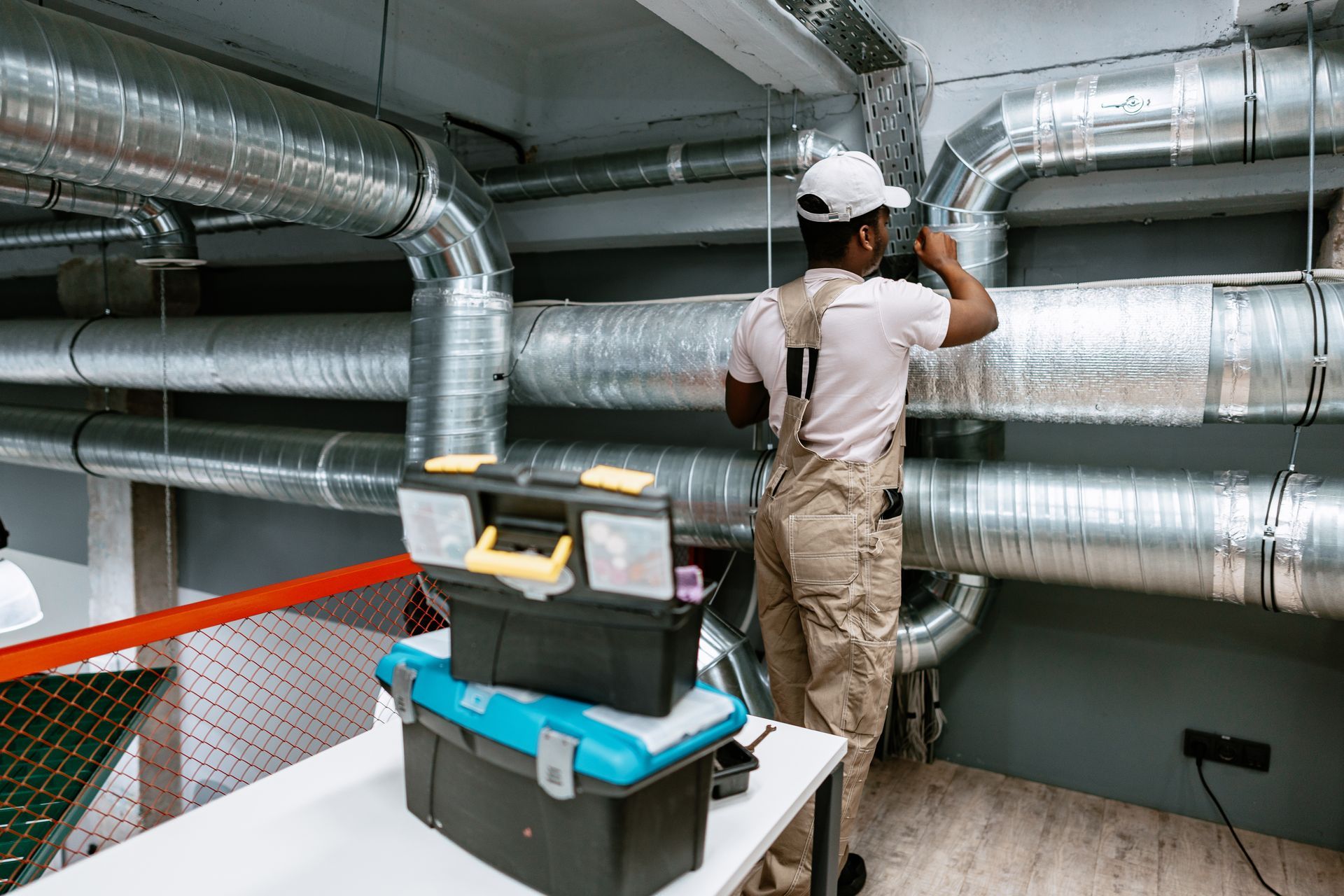 An HVAC technician installing ductwork in a modern commercial space.