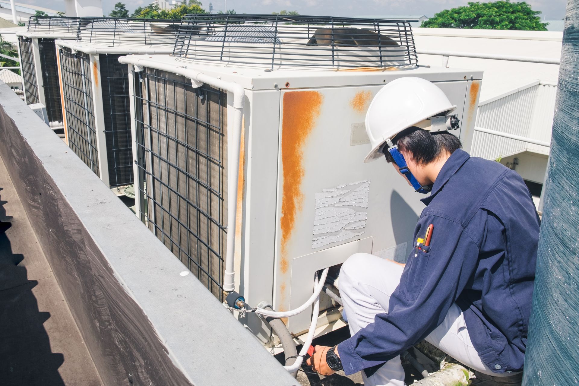 HVAC technician repairing rusty rooftop air conditioner unit during scheduled maintenance service.